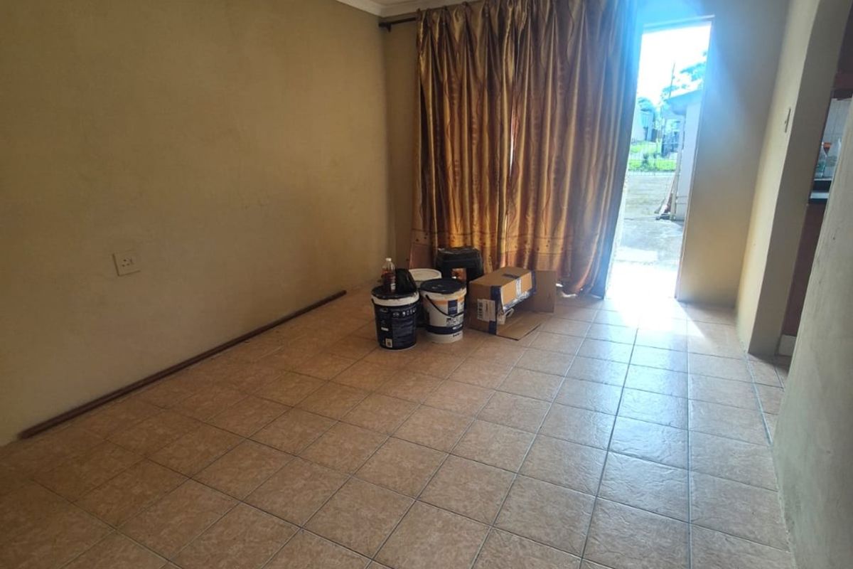 An empty living room featuring tiled flooring and direct access to an outdoor area, providing a blank canvas for renovation and interior design.