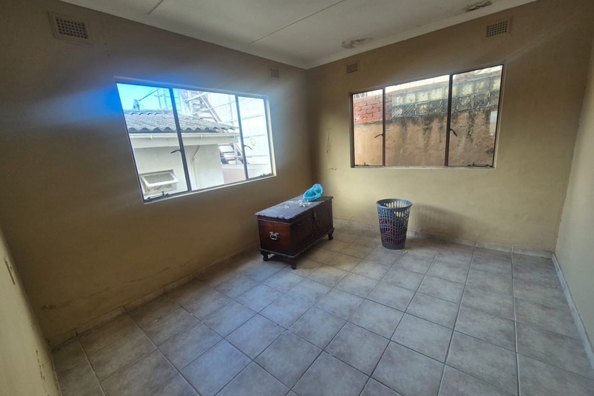 A vacant bedroom featuring tiled flooring and aluminium windows, requiring cosmetic updates to the walls and ceiling to improve its overall condition.