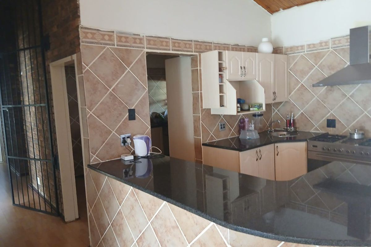 Kitchen featuring granite countertops, built-in cabinetry, stainless steel extractor fan, gas stove, and tiled splashback with a timber ceiling.