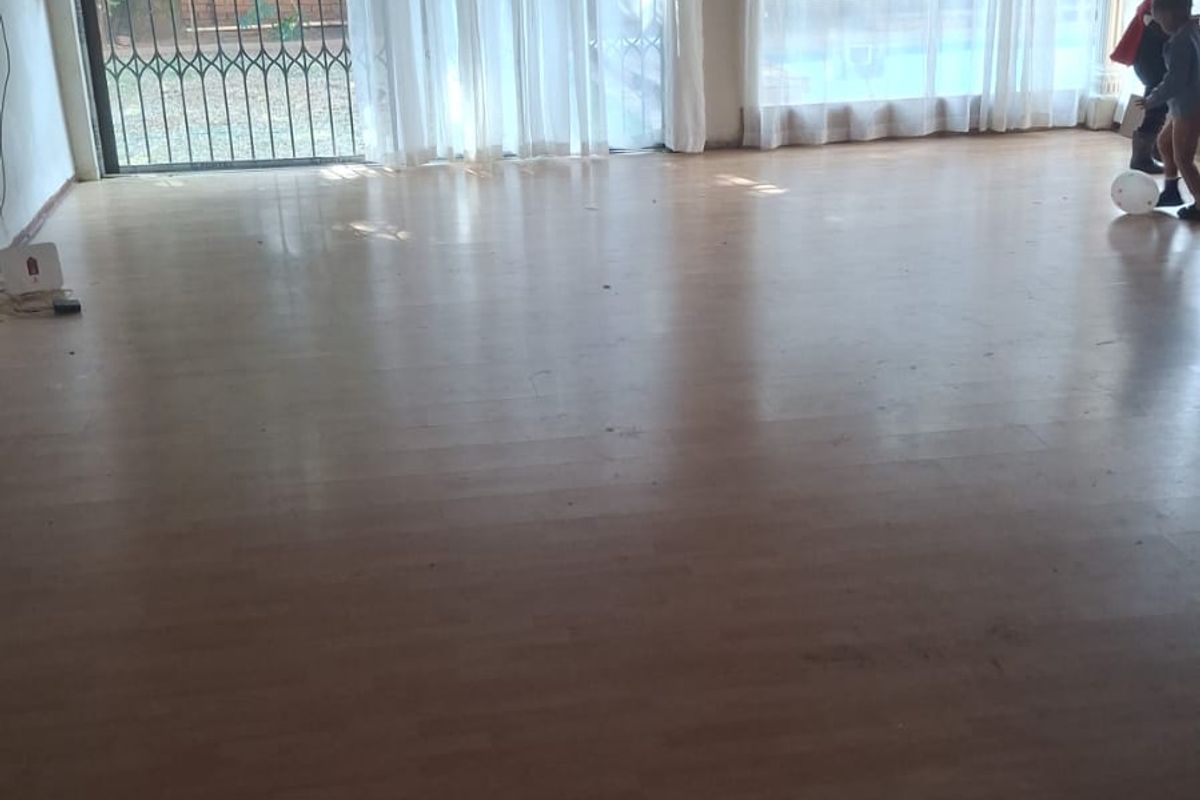 Spacious living area featuring laminate flooring, a timber-paneled ceiling, and large sliding glass doors with security gates, providing ample natural light.