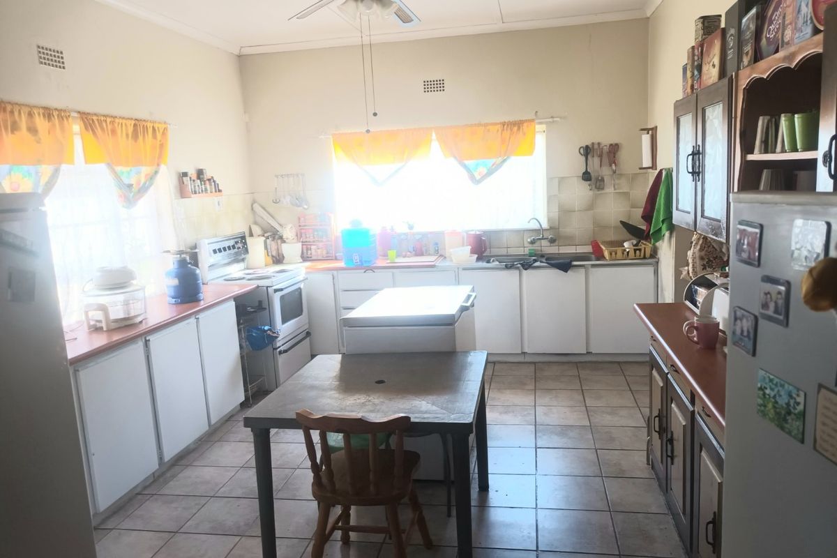 A functional kitchen featuring tiled flooring, built-in cabinetry, and a tiled backsplash, offering a practical layout with potential for modern cosmetic updates.