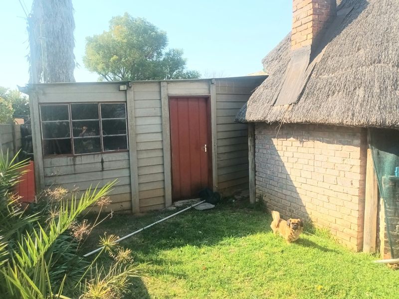 Rear view of the property showing a precast concrete structure adjacent to a traditional brick and thatched roof building.