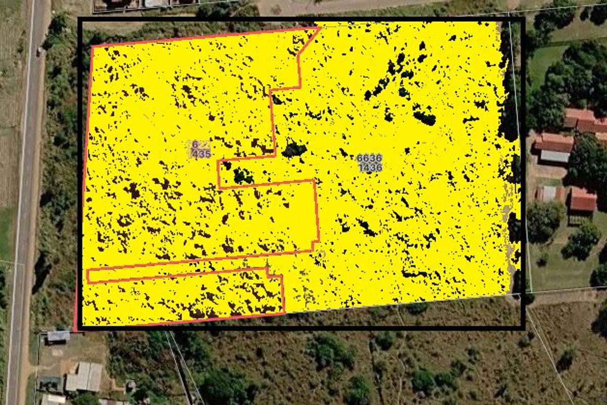 Aerial view of a vacant residential land plot with highlighted property boundaries.