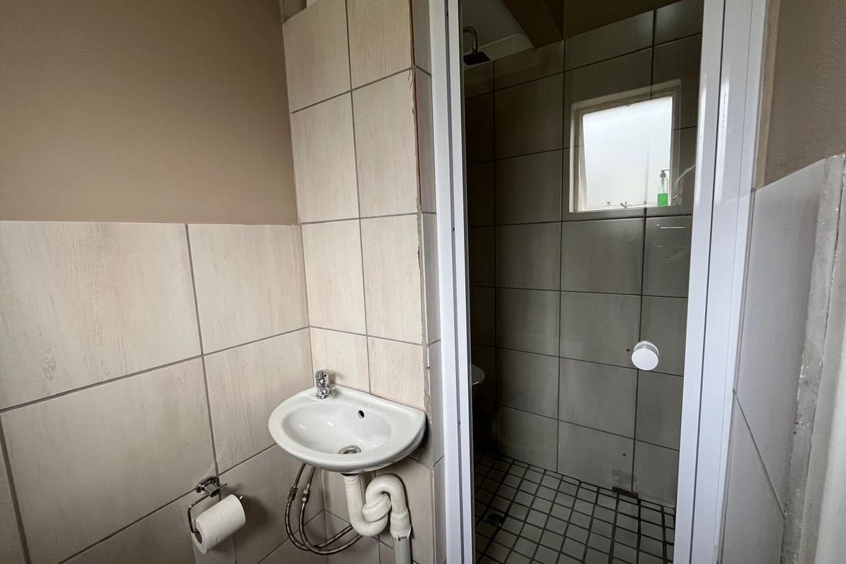 A compact bathroom featuring a wall-mounted basin, tiled finishes, and a separate shower enclosure.