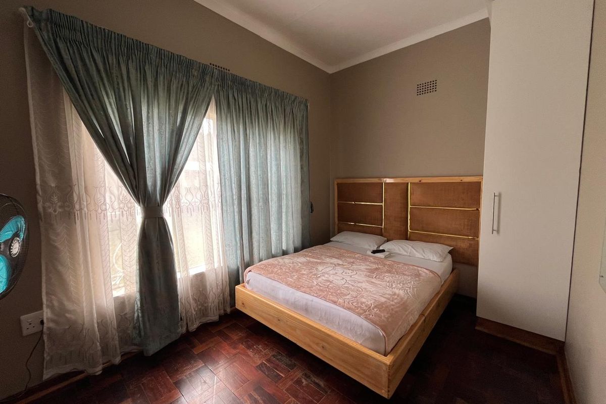 A bedroom featuring classic parquet flooring, a built-in wardrobe, and neutral wall tones, offering a functional and well-maintained living space.