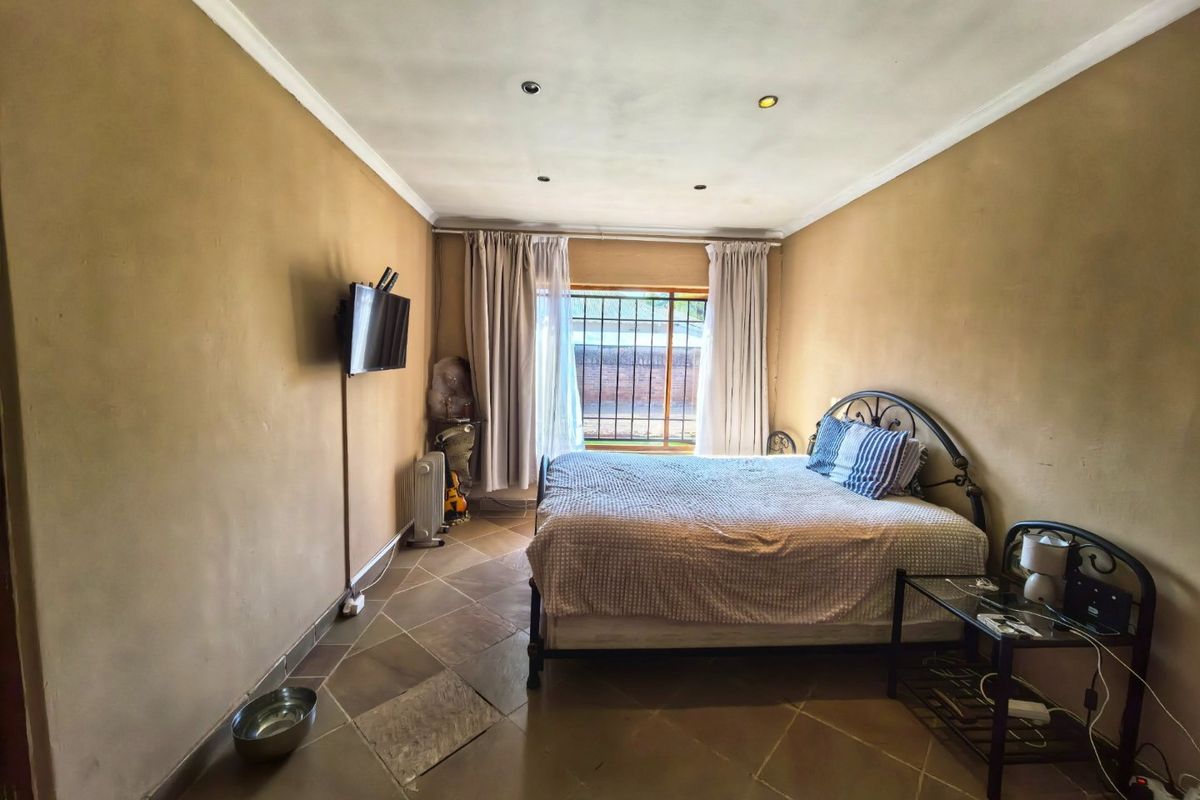 A bedroom featuring tiled flooring, recessed downlighting, and security bars on the window. The room requires cosmetic updates to improve its overall condition.