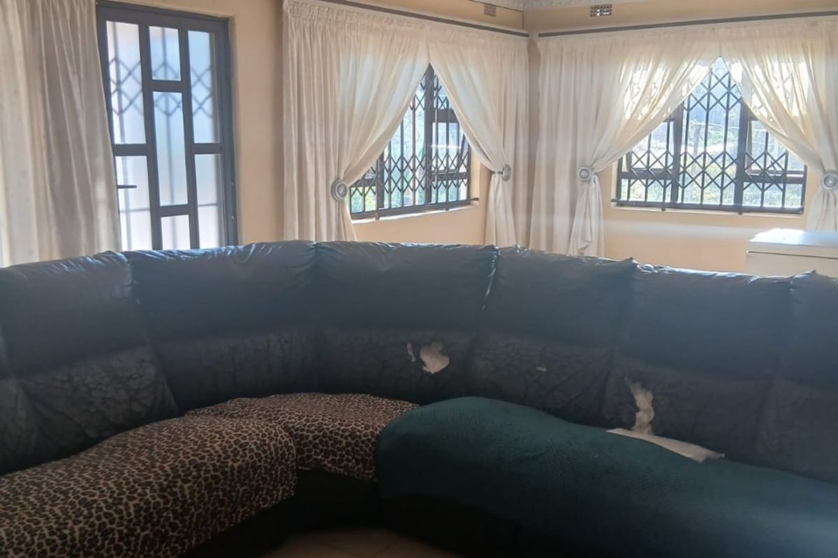 A living room featuring tiled flooring, recessed ceiling details, and security gates on the windows, providing a functional and secure living space.