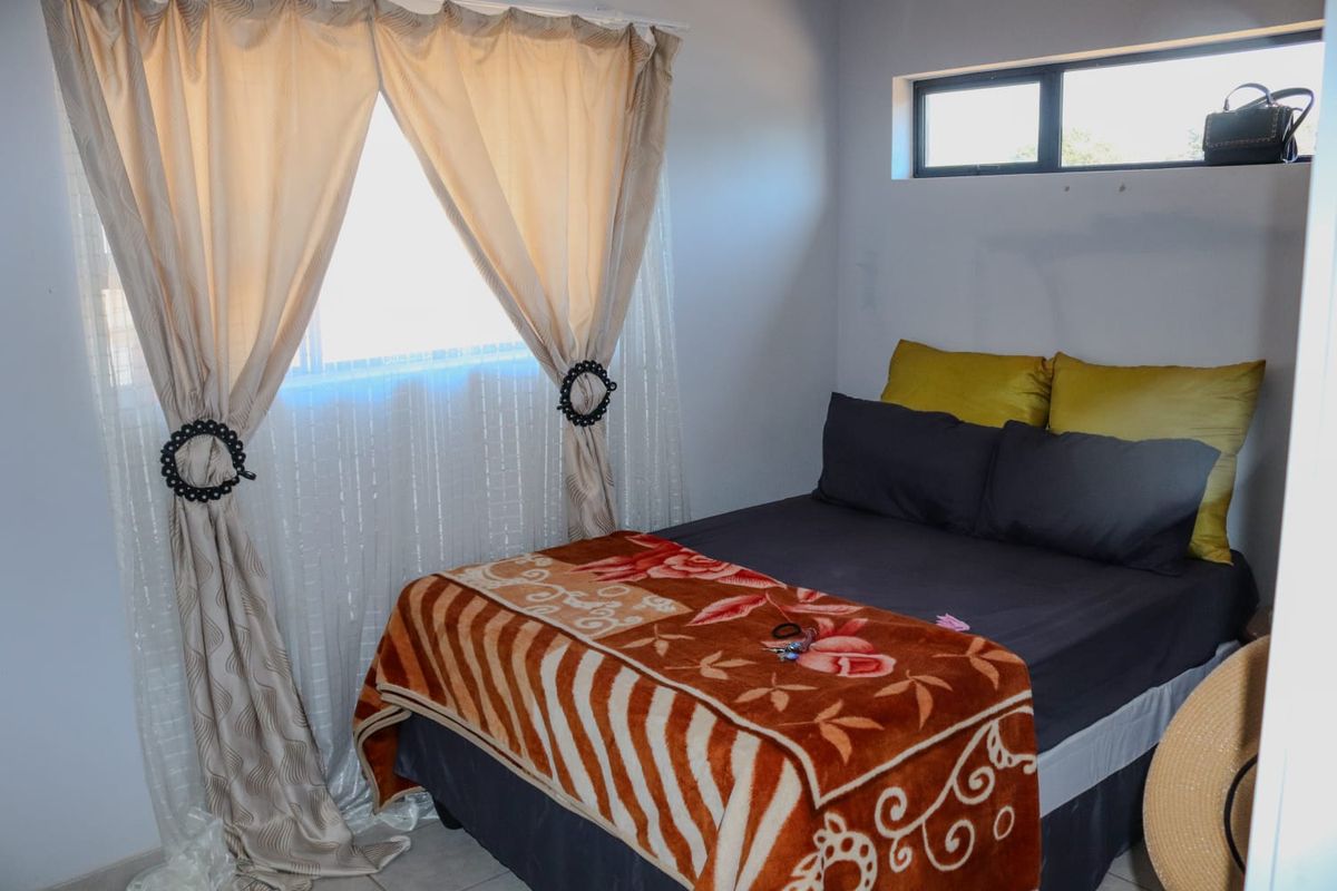 A functional bedroom featuring a large window with curtains and a high-level clerestory window for natural light.