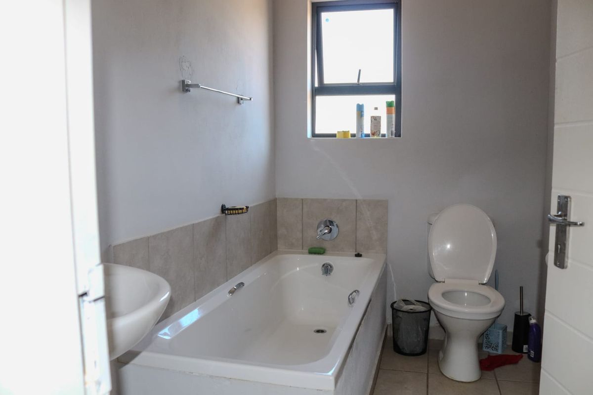 A functional bathroom featuring a bathtub, toilet, and basin with tiled splashbacks and neutral flooring.