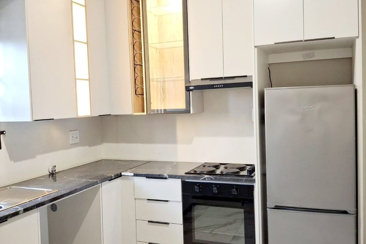 Modern kitchen featuring sleek white cabinetry, marble-effect flooring, integrated oven and hob, and stylish under-cabinet lighting in a clean, contemporary finish.