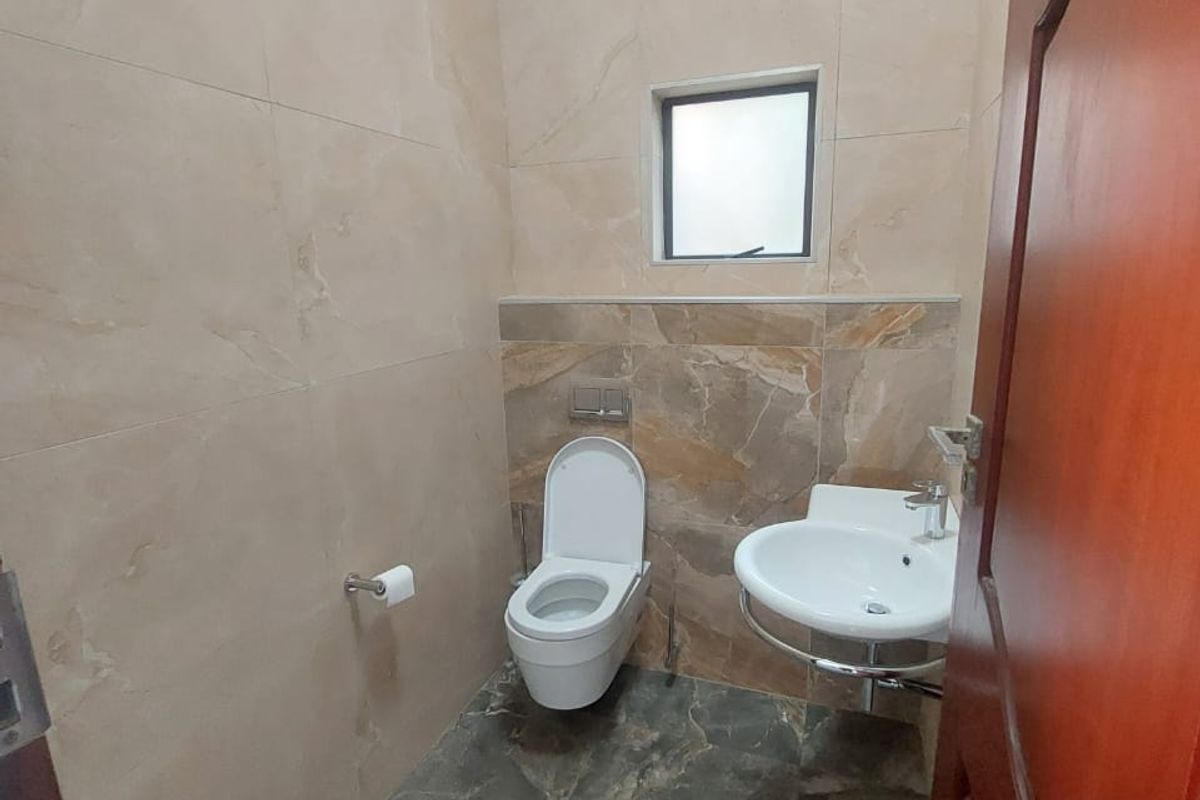 A compact, modern bathroom featuring floor-to-ceiling marble-effect tiling, a wall-mounted toilet, and a sleek wall-mounted basin.