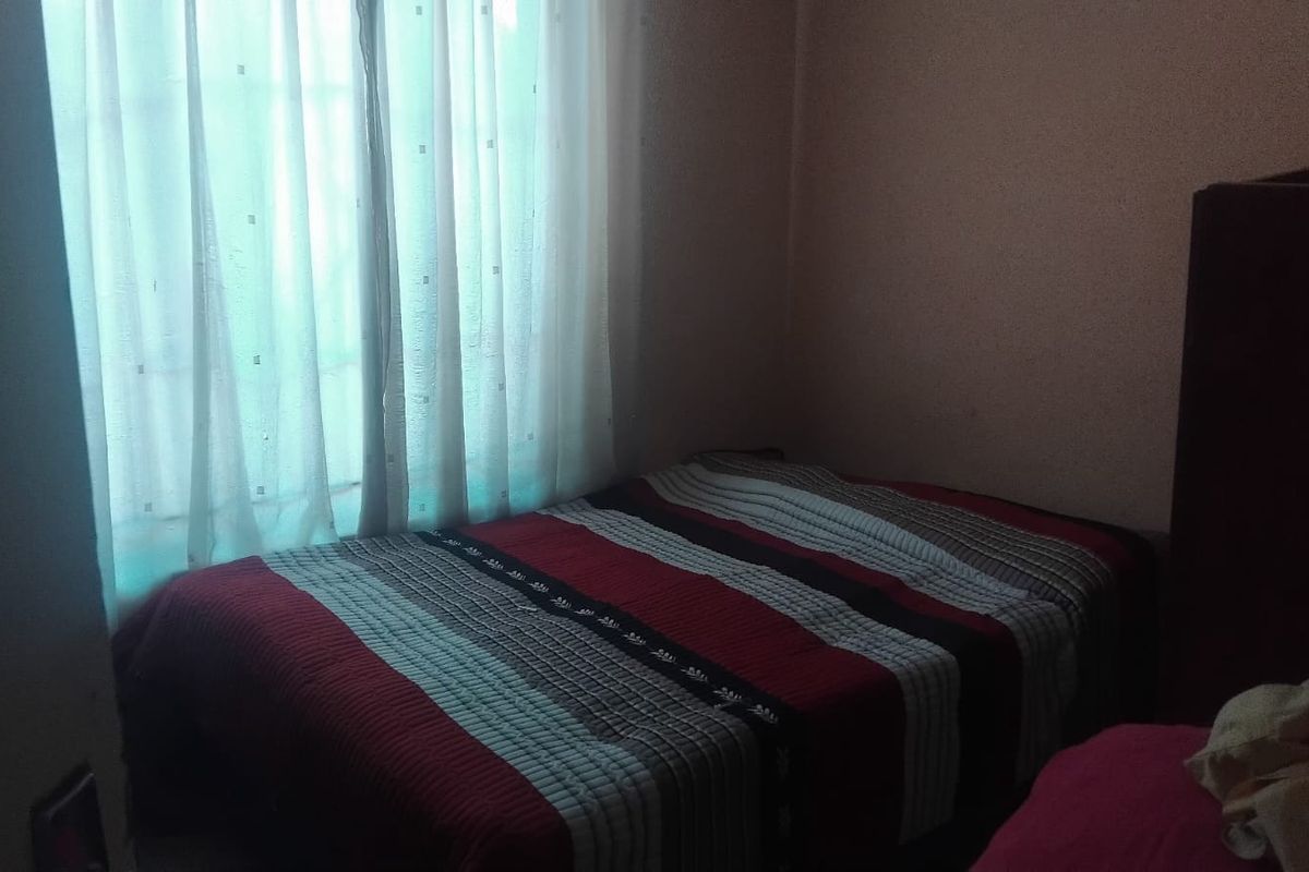 A bedroom featuring a window with curtains, providing natural light to the space.