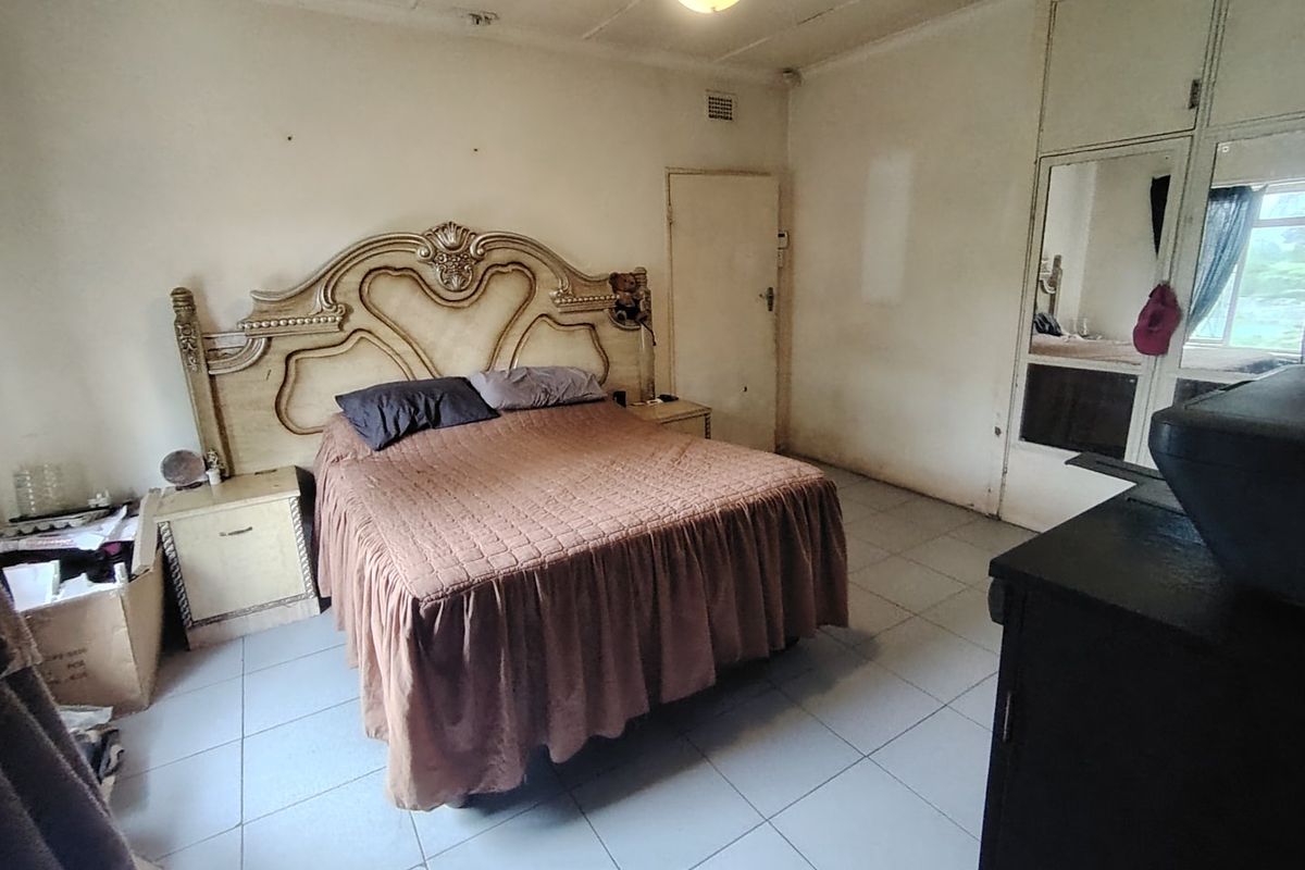 A bedroom featuring tiled flooring and built-in mirrored wardrobes, requiring cosmetic updates to modernize the space.