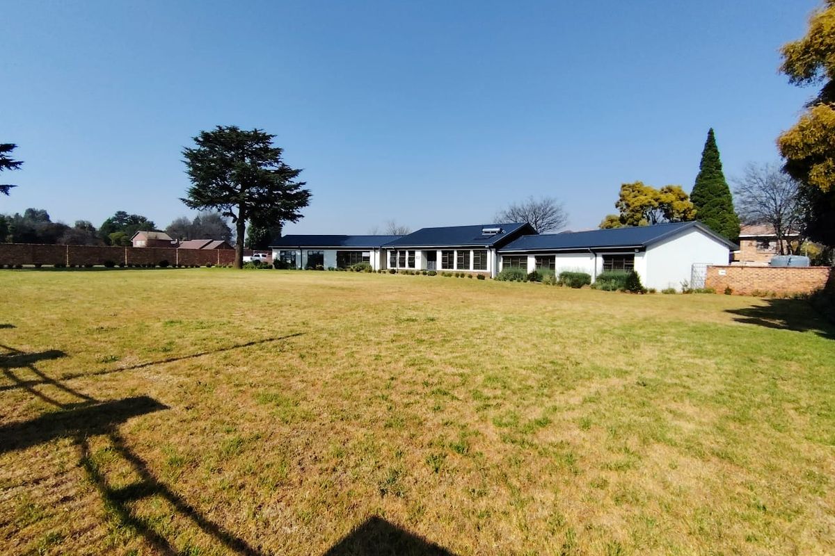 A wide-angle view of the rear elevation of the house, featuring a modern metal roof and a spacious, well-maintained lawn.