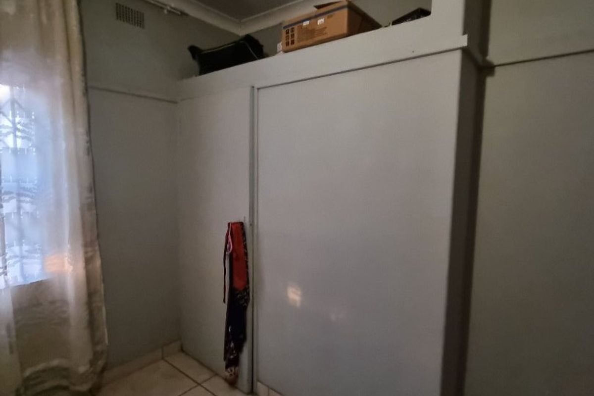 A bedroom featuring built-in cupboards with a neutral paint finish and tiled flooring throughout.