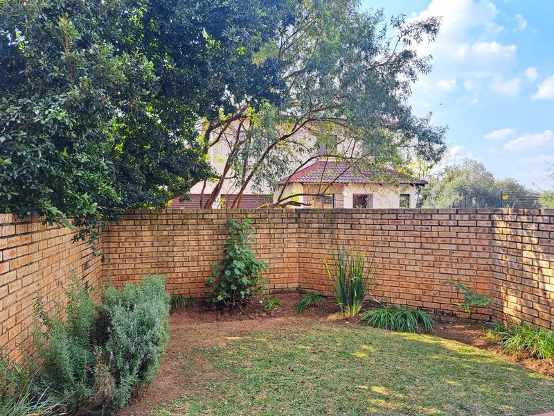 A private rear garden area featuring a well-maintained brick boundary wall and established garden beds with lawn.