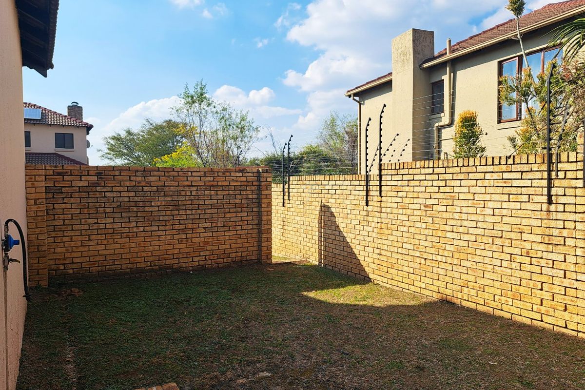 A private rear garden area featuring brick boundary walls, integrated electric fencing, and a small paved section.