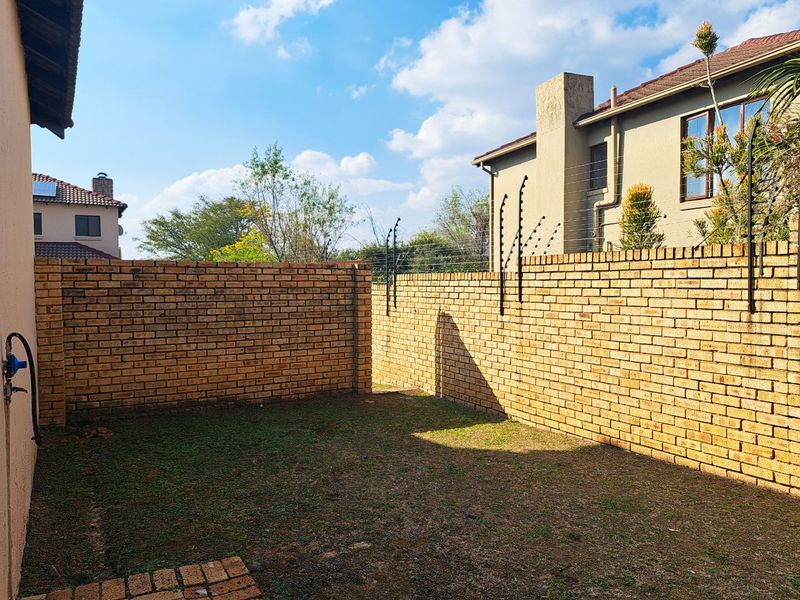 A private rear garden area featuring brick boundary walls, integrated electric fencing, and a small paved section.