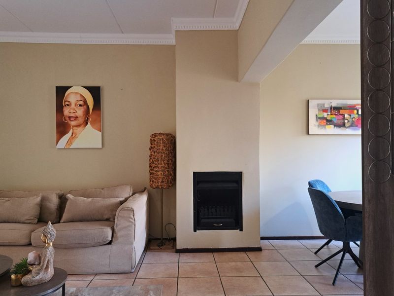 Open plan living and dining area featuring ceramic floor tiles, a built-in fireplace, and decorative ceiling cornicing.