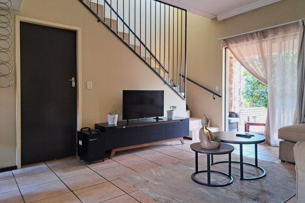Living room featuring tiled flooring, a staircase with a metal balustrade, and a sliding glass door providing access to the outdoor patio area.