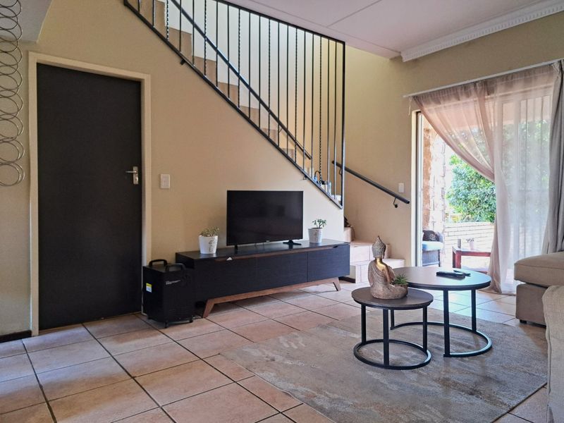 Living room featuring tiled flooring, a staircase with a metal balustrade, and a sliding glass door providing access to the outdoor patio area.