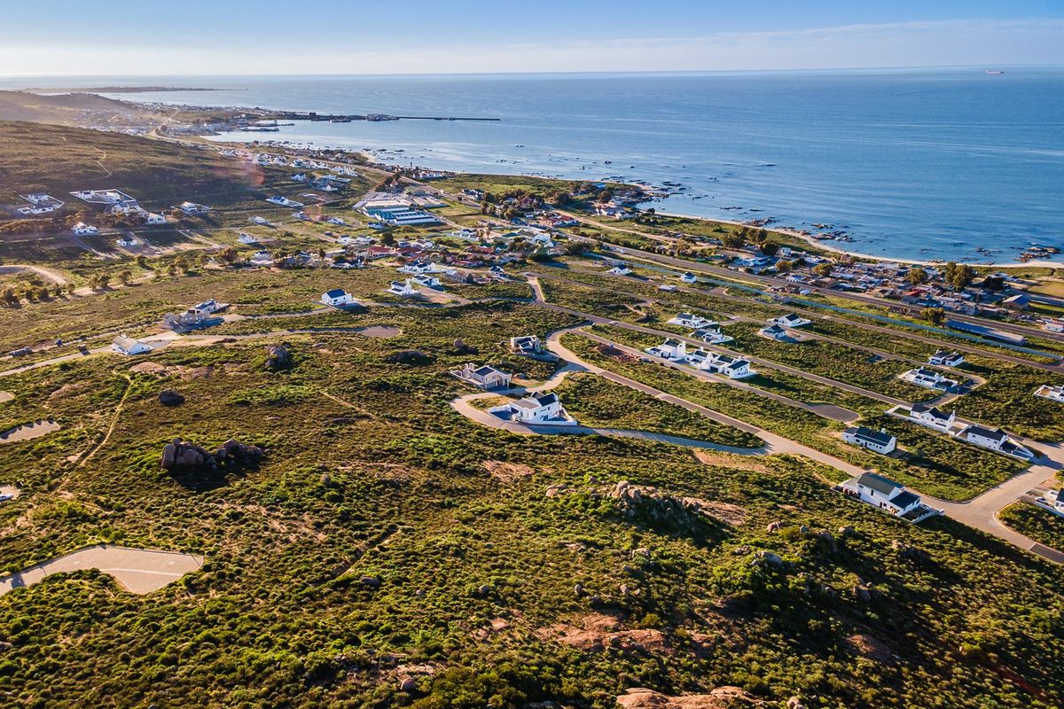 An expansive aerial view of a coastal residential development featuring established road infrastructure and proximity to the ocean.