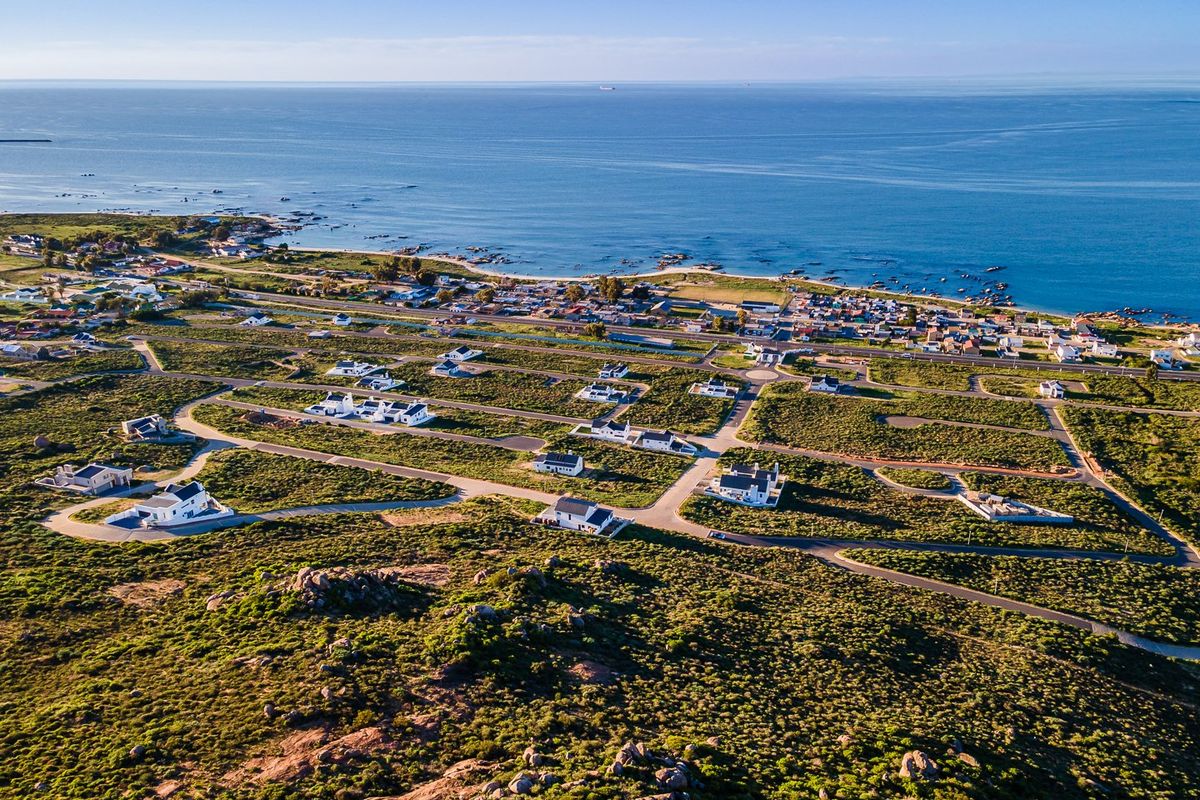 An aerial view of a coastal residential development featuring paved roads and established homes overlooking the ocean.