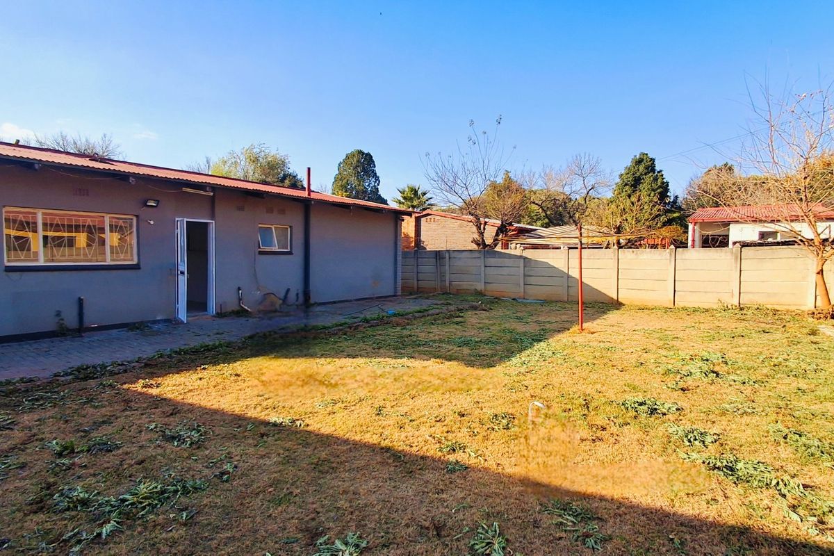 Rear view of the property featuring a paved patio area, a large backyard, and a precast concrete boundary wall.