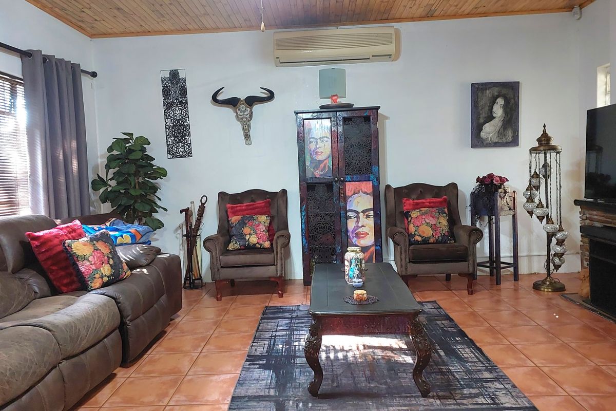 A living room featuring tiled flooring, a timber-paneled ceiling, and a wall-mounted split-system air conditioner.