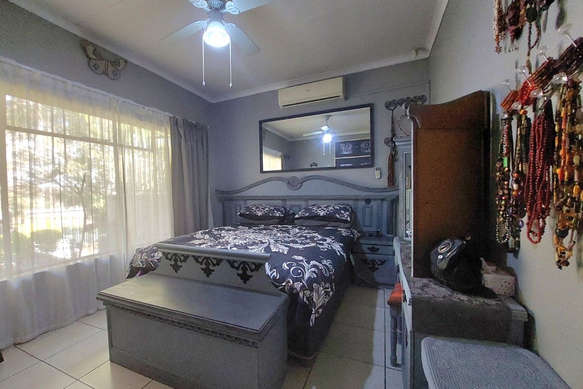 A bedroom featuring tiled flooring, a ceiling fan, and a wall-mounted split-system air conditioner.