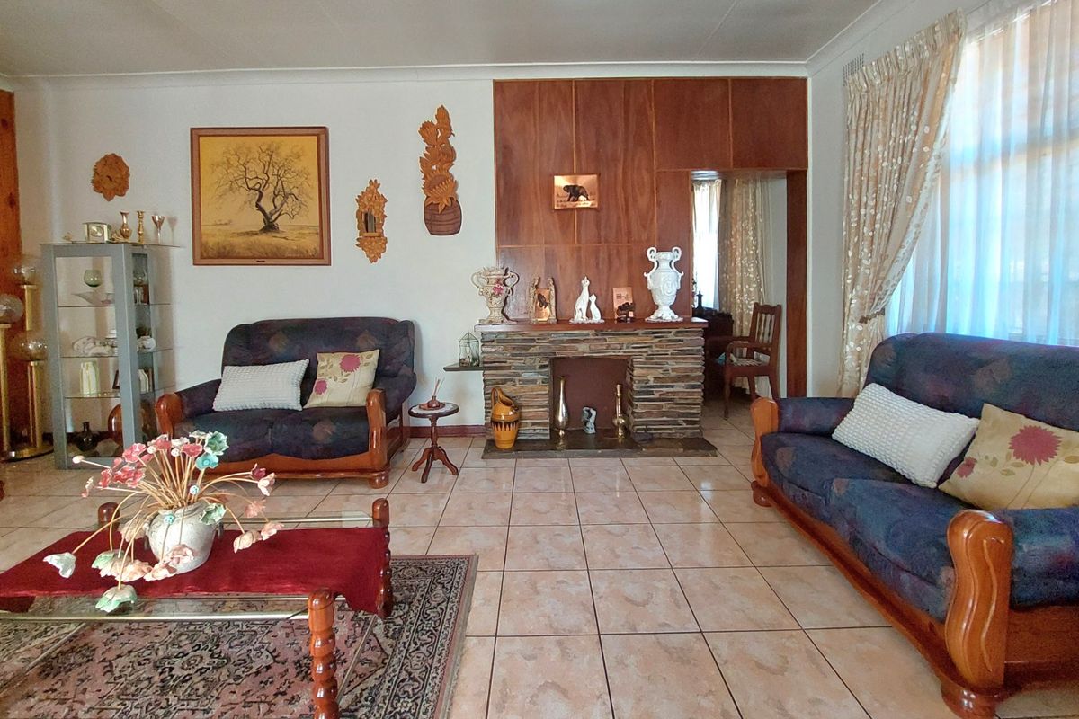 Spacious living room featuring a stone fireplace, wood paneling accents, and ceramic floor tiles throughout.