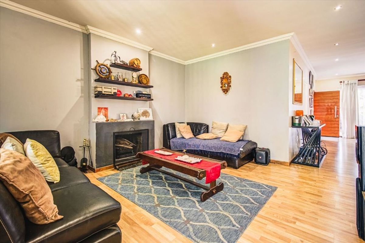 A cozy living room featuring a built-in fireplace, recessed downlighting, and warm wooden flooring, creating a comfortable and inviting atmosphere.