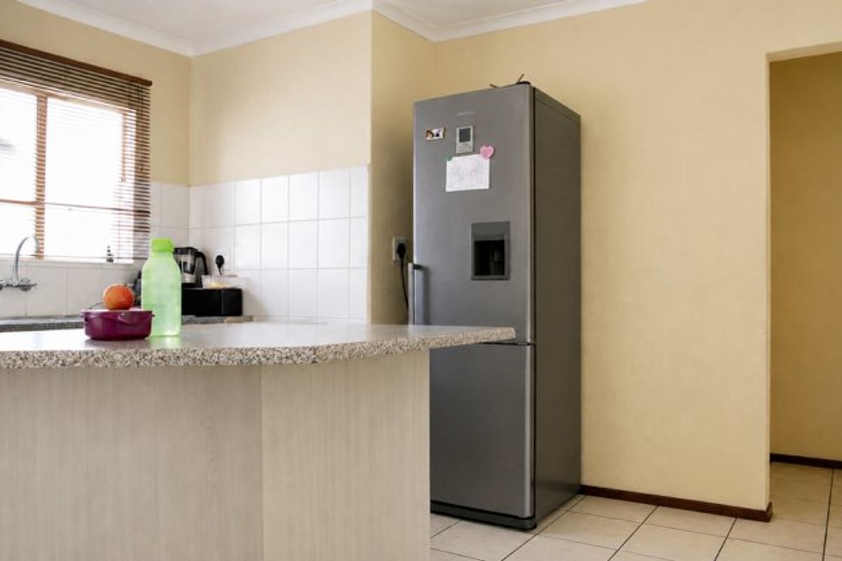 A functional kitchen area featuring a granite breakfast bar, tiled backsplash, and neutral wall finishes, providing a practical space for daily meal preparation.