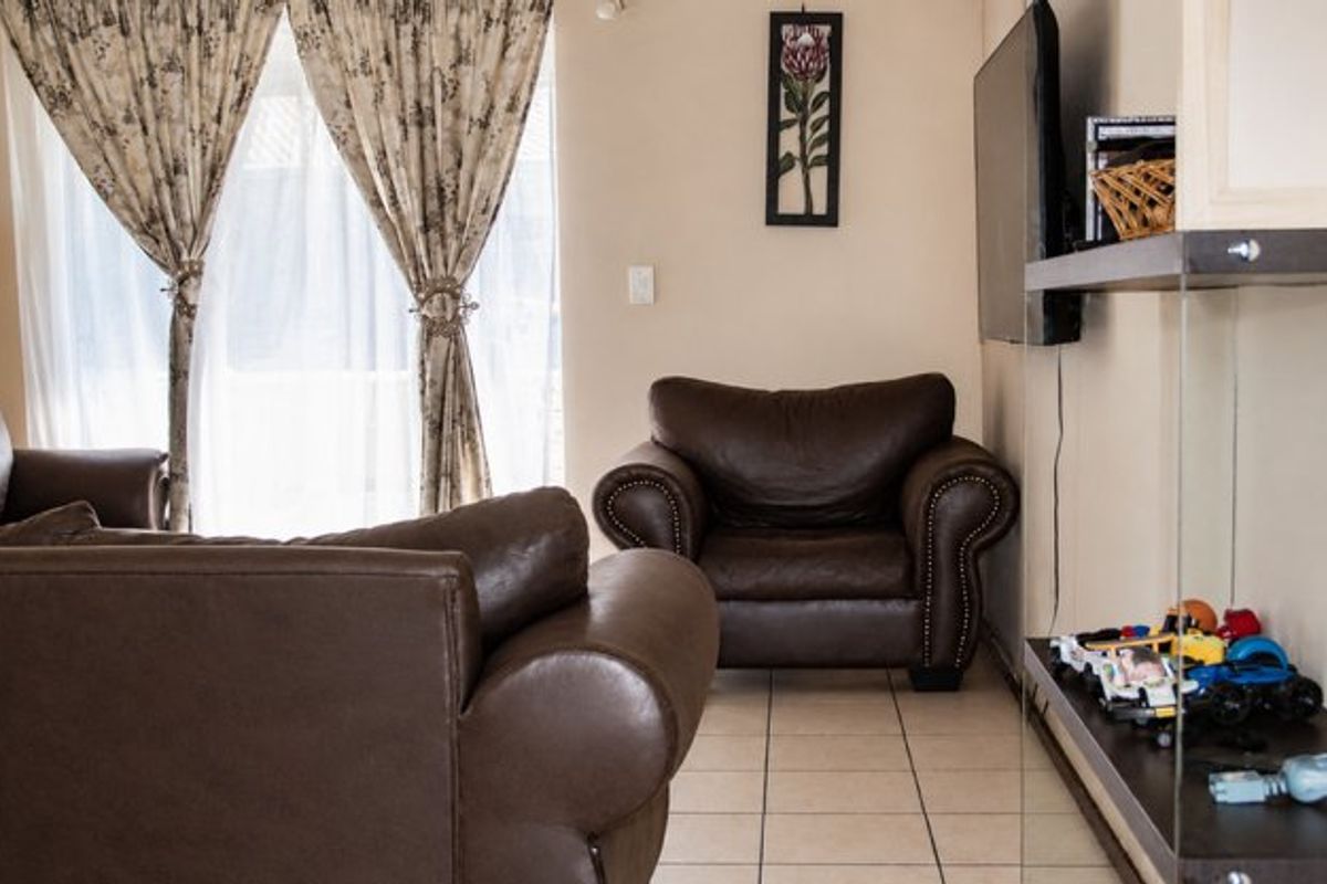 A living room area featuring tiled flooring and a sliding glass door providing natural light.