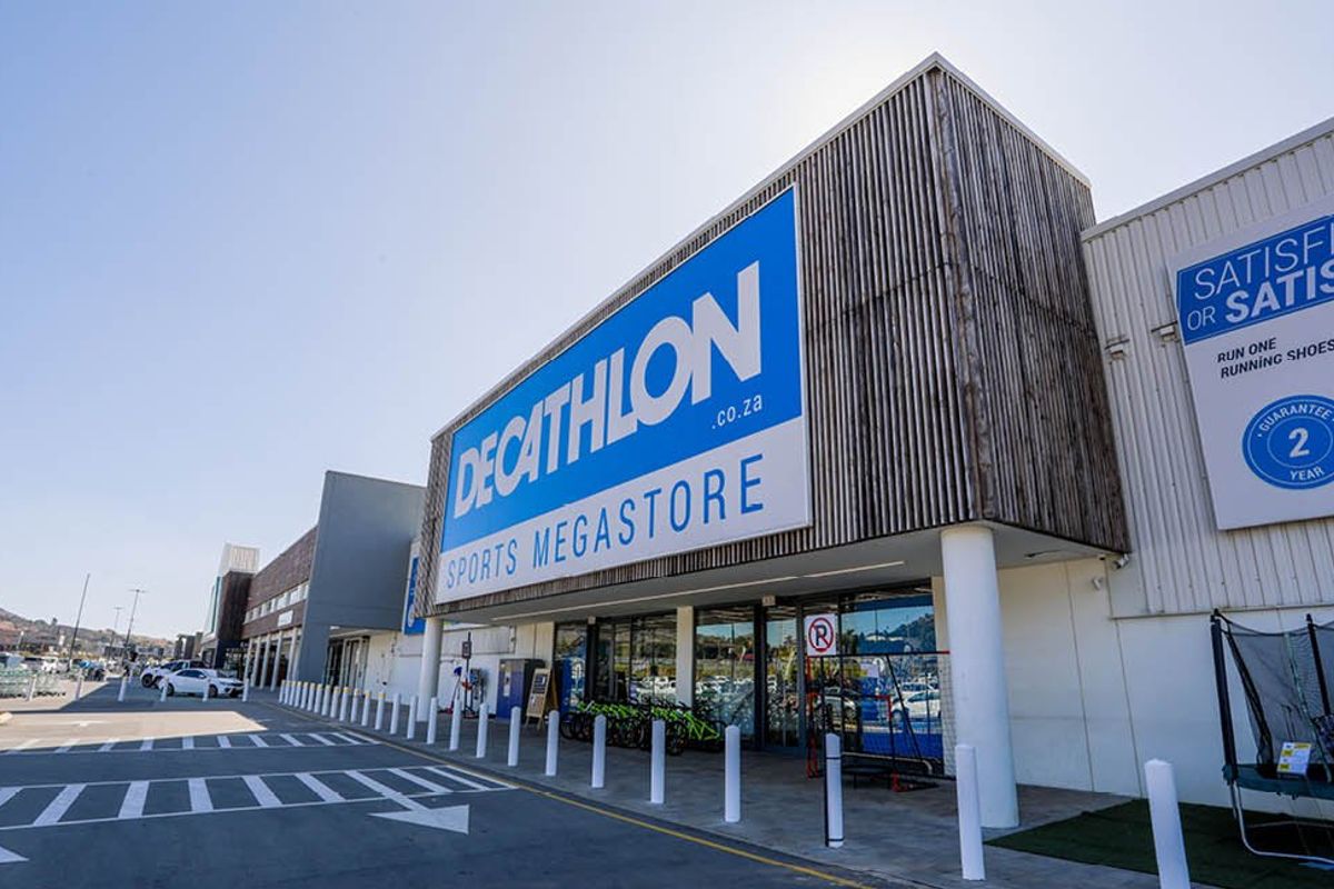 Front elevation of a commercial sports megastore featuring modern timber cladding, large signage, and a paved parking area.