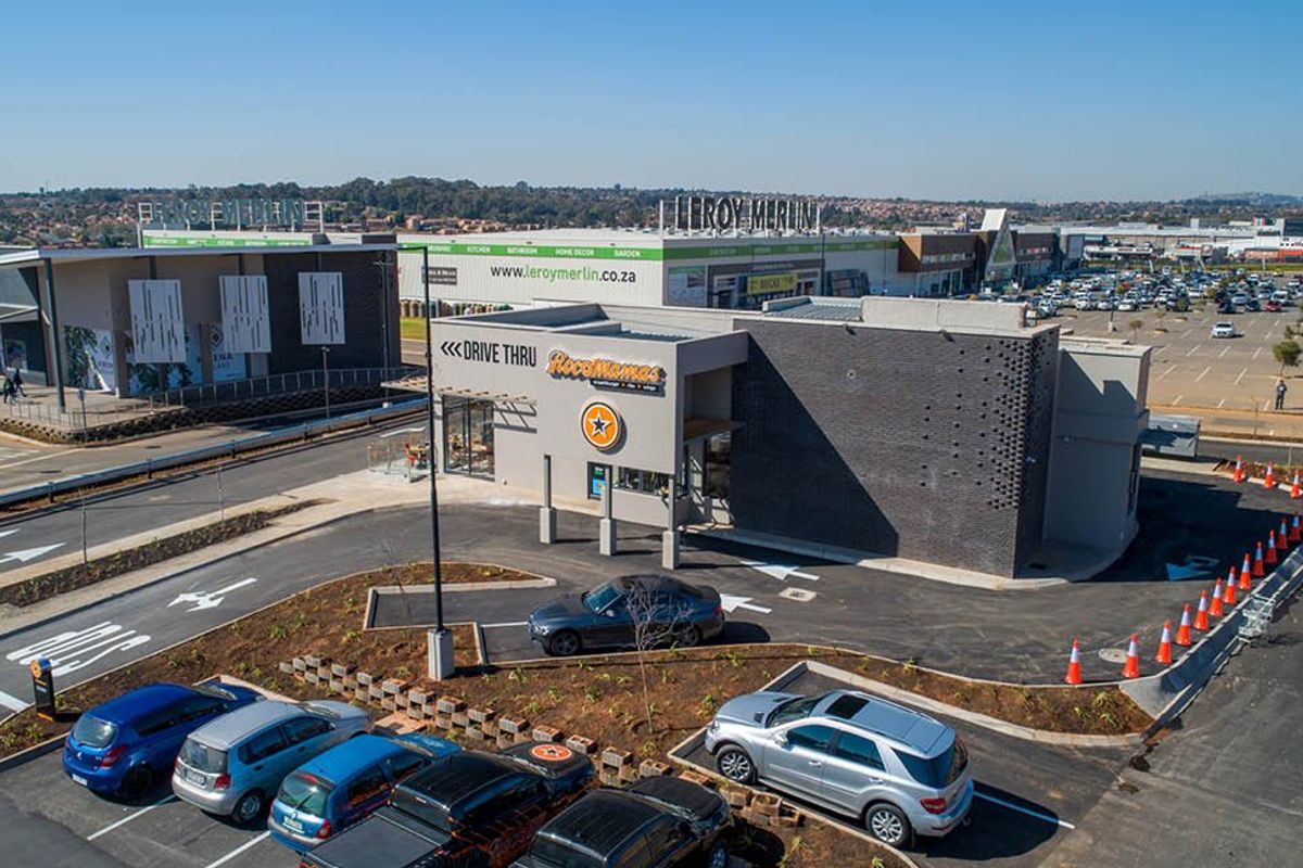 Aerial view of a modern commercial property featuring a drive-thru facility, paved parking area, and landscaped surroundings within a retail complex.