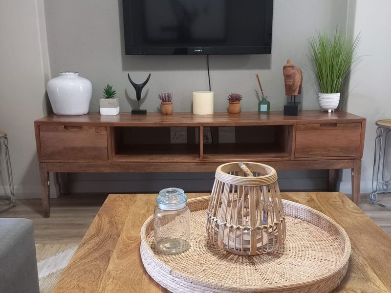 A well-maintained living room area featuring laminate flooring and a wall-mounted television setup.