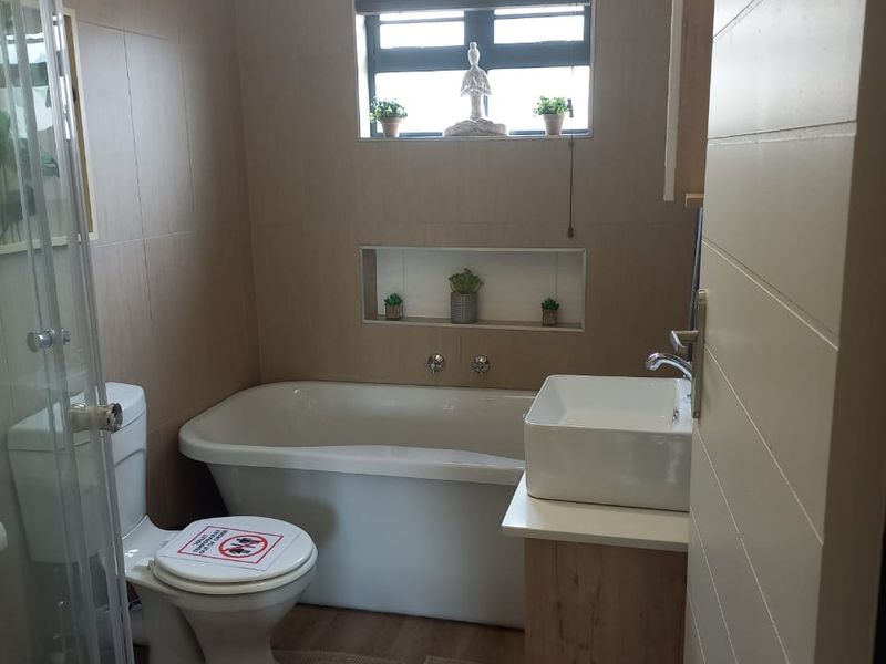 Modern bathroom featuring a freestanding bathtub, glass shower enclosure, vessel sink with vanity cabinet, and a convenient recessed wall niche.