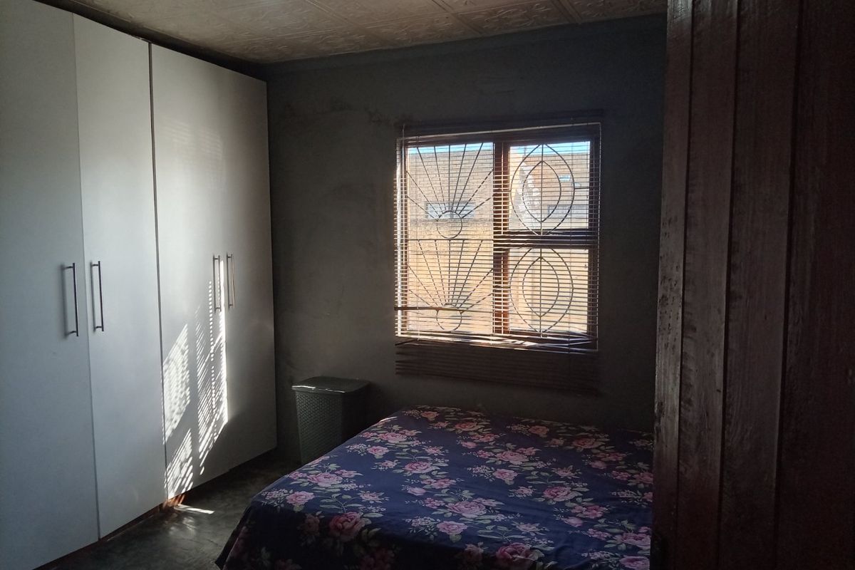 A bedroom featuring a built-in wardrobe, security gate on the window, and a textured ceiling finish.