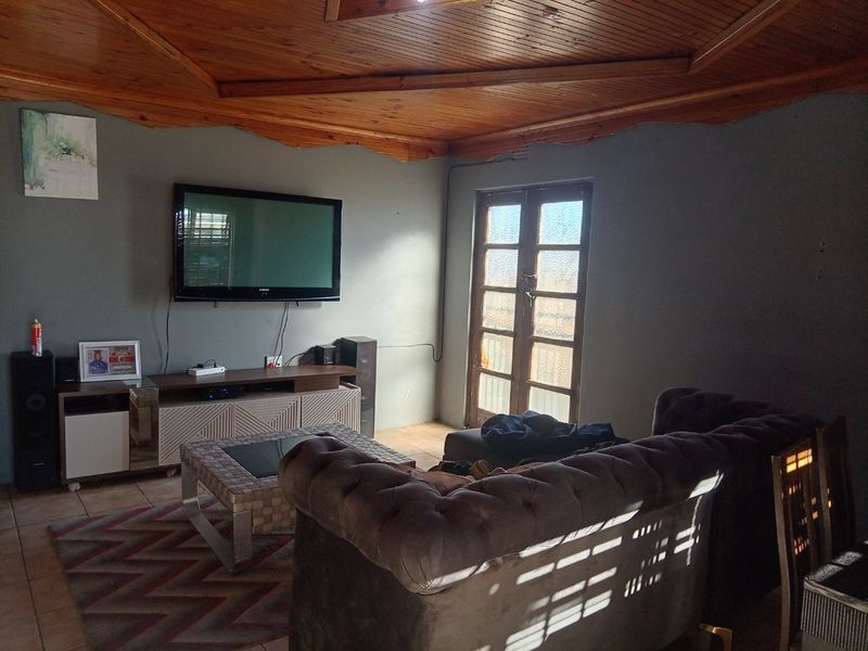 A living room featuring a distinctive timber-clad vaulted ceiling, tiled flooring, and french doors providing natural light.
