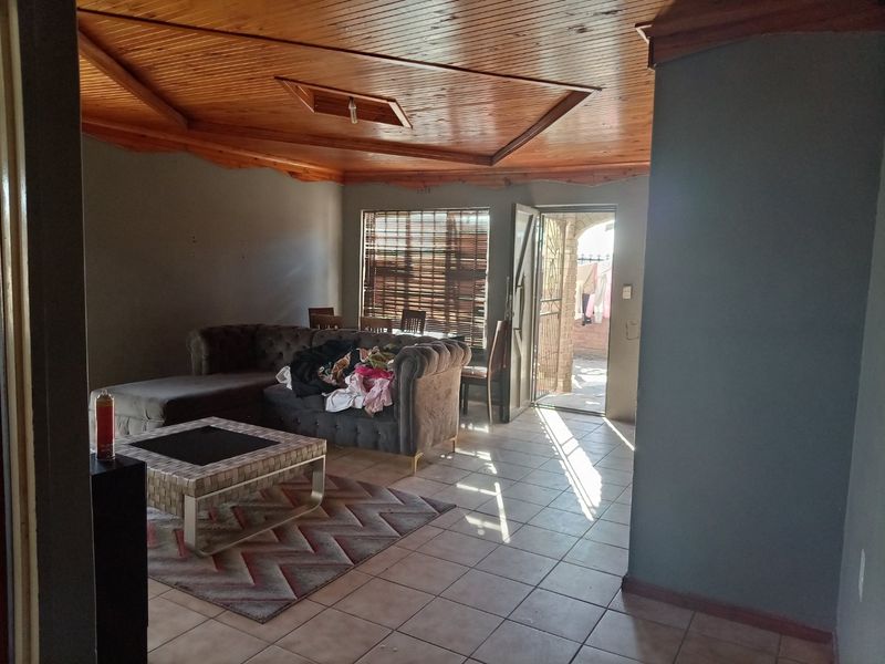 Spacious living area featuring a distinctive timber tongue and groove ceiling, ceramic tiled flooring, and direct access to an outdoor patio area.