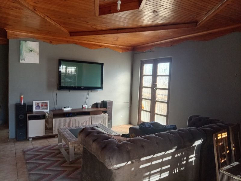 A living room featuring a distinctive timber-clad vaulted ceiling, tiled flooring, and access to the exterior via classic french doors.