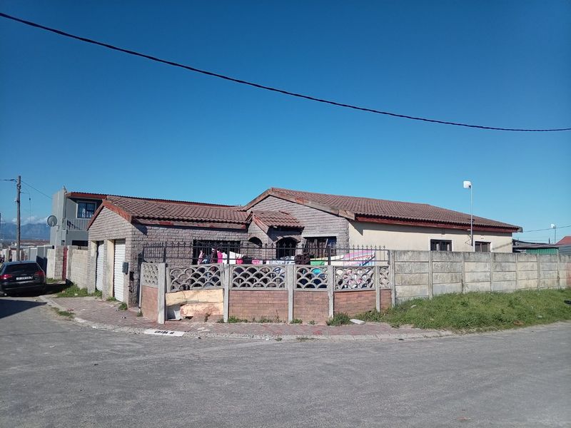 Front exterior view of a single-story house featuring a tiled roof, brick facade, and a perimeter boundary wall with a security gate.