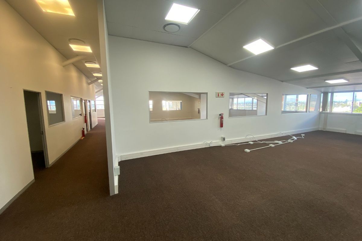 Spacious open-plan commercial office area featuring carpeted flooring, recessed LED lighting, and internal glass partitions, providing a bright and functional workspace.