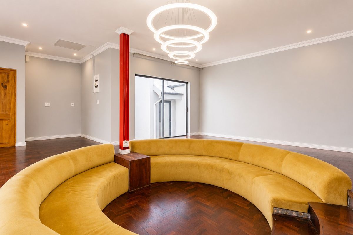 Spacious living area featuring rich parquet flooring, decorative crown molding, a prominent structural column, and a modern circular chandelier.