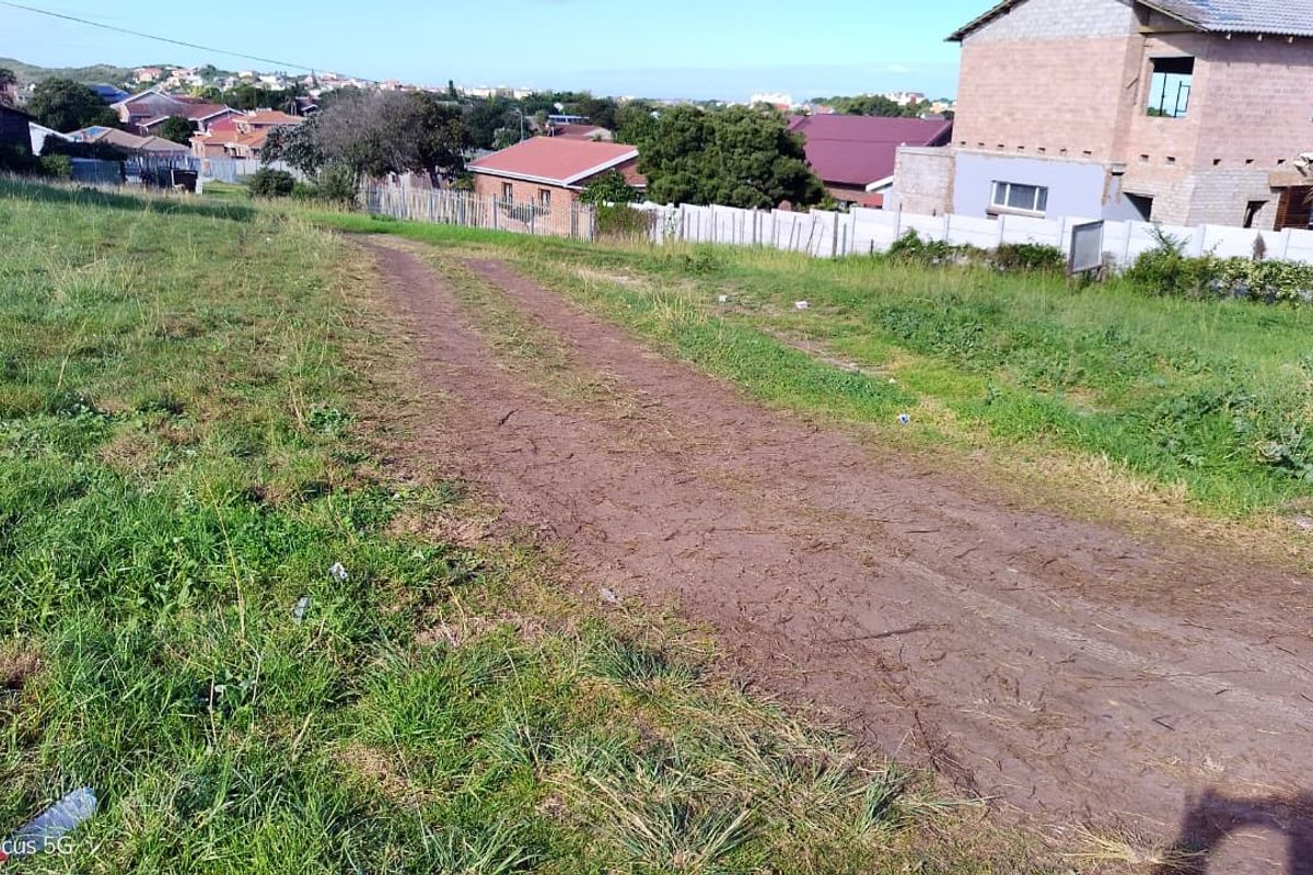 A view of a vacant residential plot featuring an unpaved access track and surrounding grass, situated in a developed neighborhood.