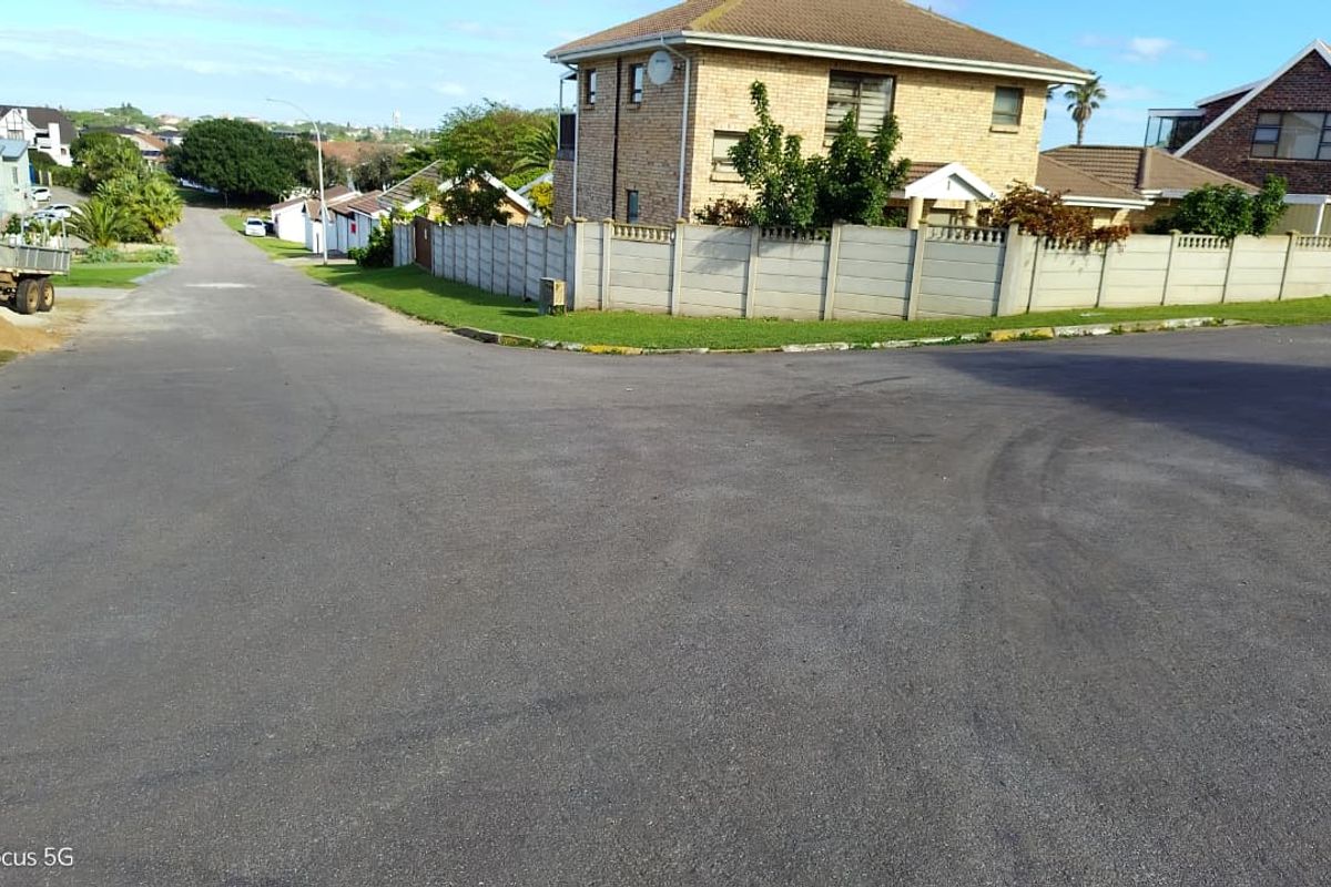 A street-level view of the residential corner lot, featuring paved road access and established concrete boundary walling.