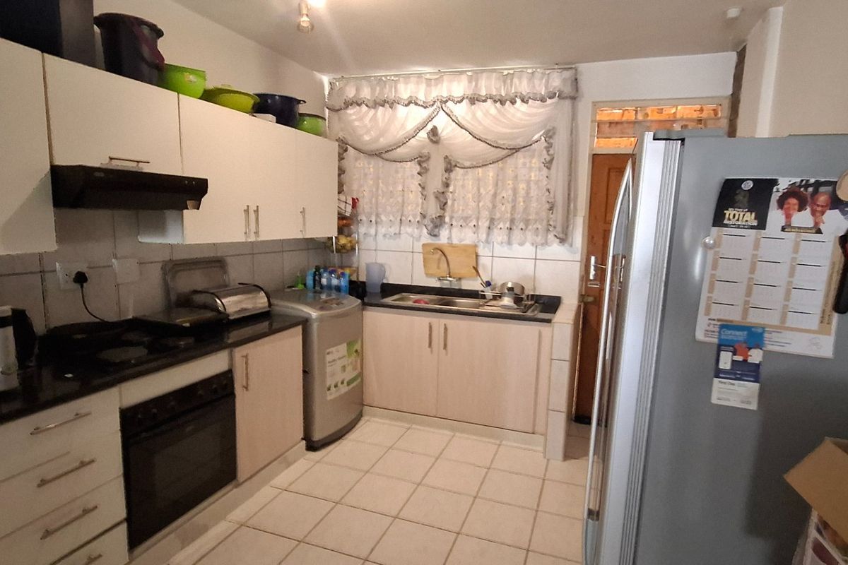 A functional kitchen featuring built-in cabinetry, laminate countertops, a stainless steel sink, and a built-in oven with an extractor fan.
