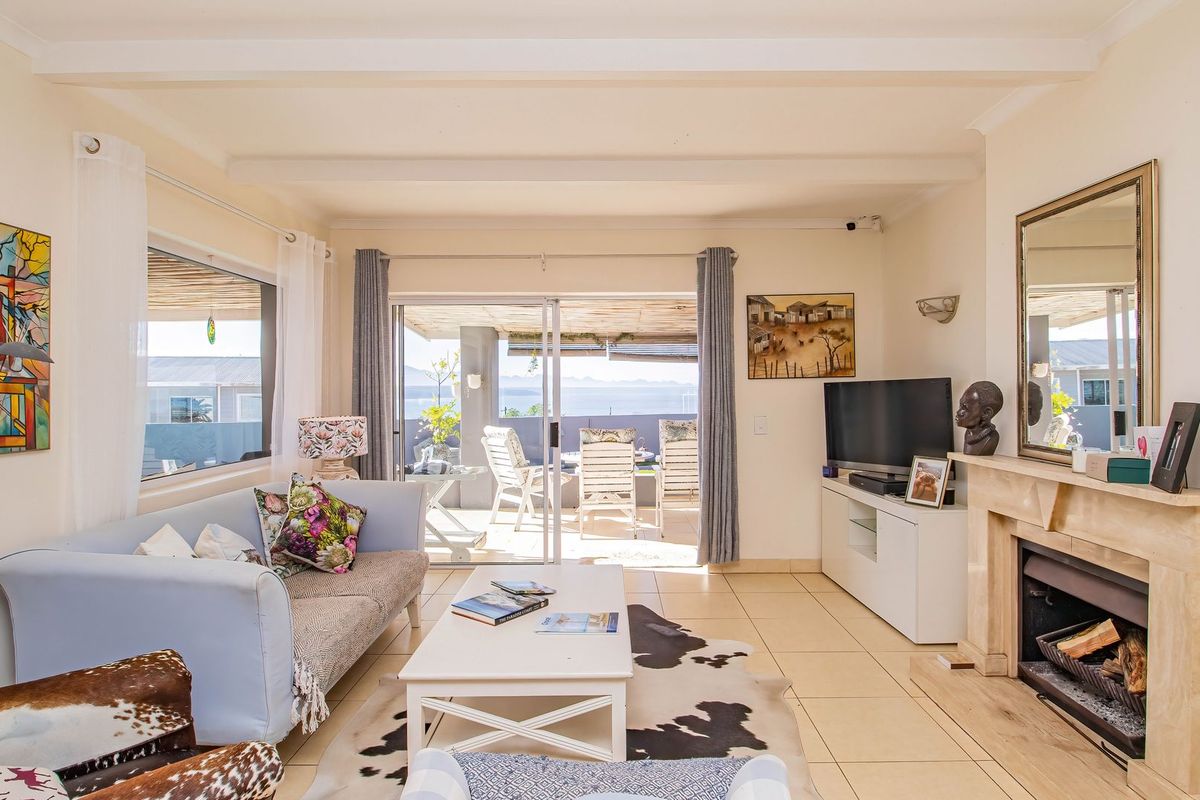 Bright living room featuring a stone fireplace, tiled flooring, and large sliding glass doors that open onto a patio with scenic views.