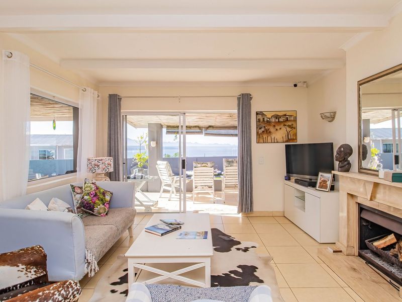 Bright living room featuring a stone fireplace, tiled flooring, and large sliding glass doors that open onto a patio with scenic views.